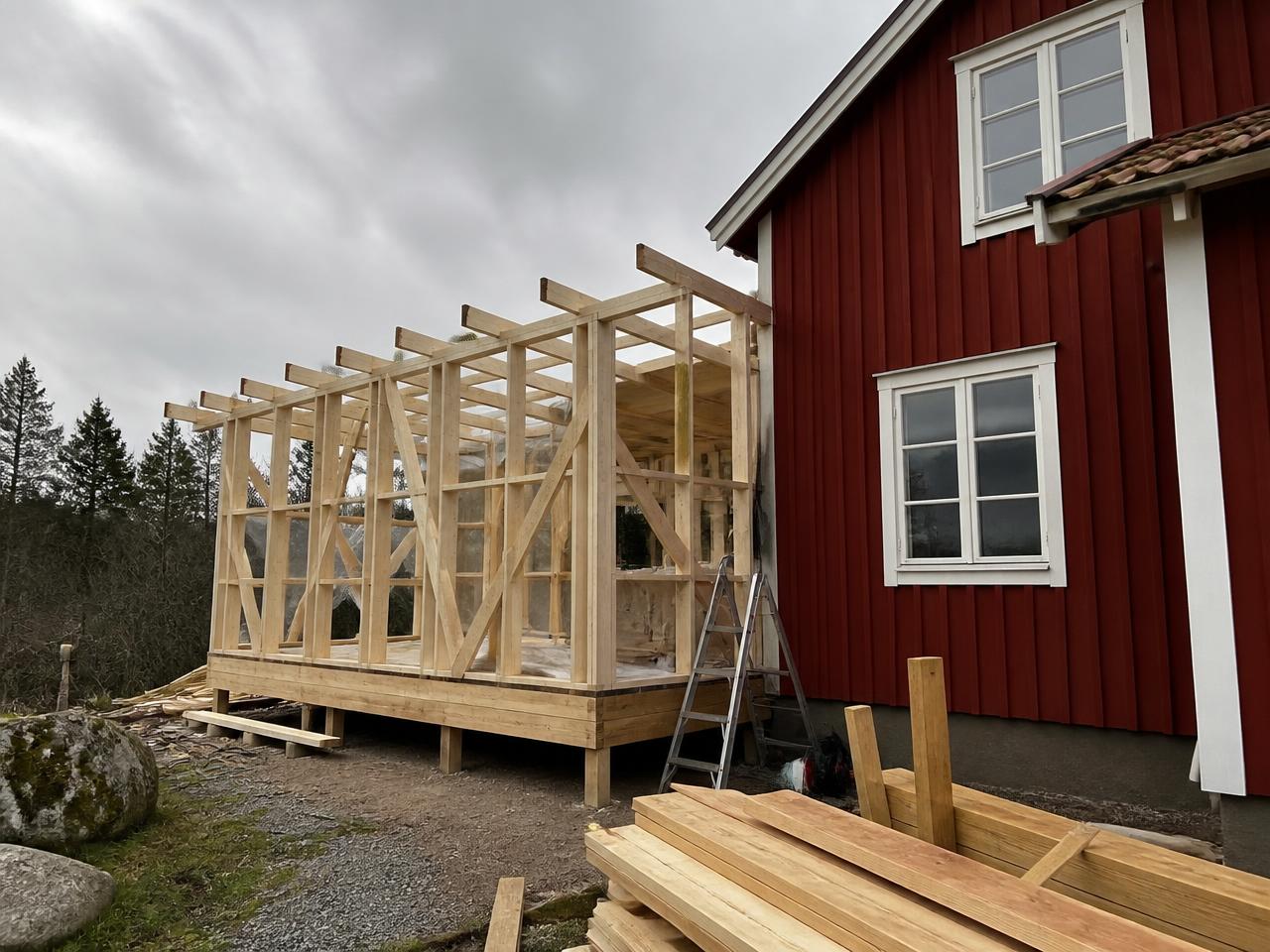 Tillbyggnad i trästomme som ansluts till ett rött trähus